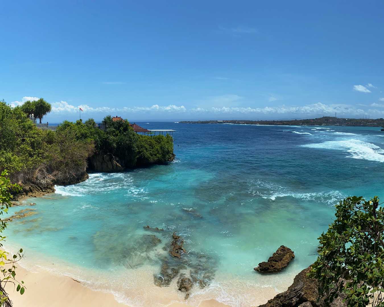 Clifftop view over Nusa Lembongan with turquoise water and traditional boats